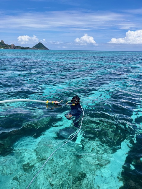 美ら海の上で収穫パイプを手にする生産者・海人勇多さん
